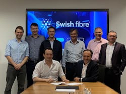 Rob Skinner, Octopus, with Brice Yharrassarry, CEO of Swish Fibre, signing their new agreement supported by their respective teams.