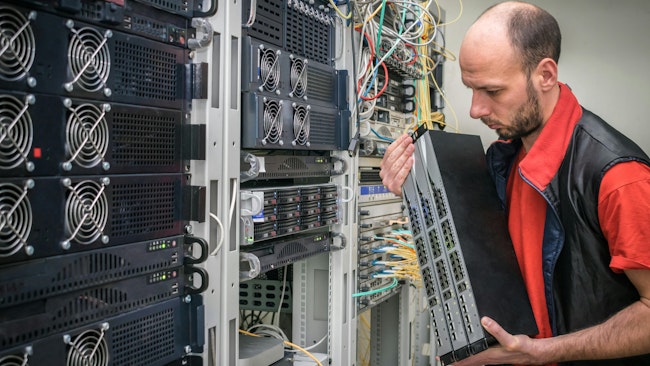 A man installing equipment in a server room.