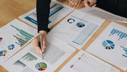 Businesspeople holding pens over graph paper. Businesspeople holding pens over graph paper.