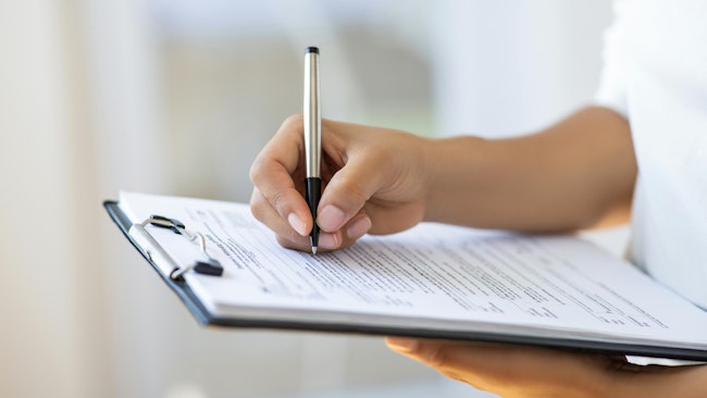 A hand writing on a clipboard.