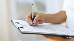 A hand writing on a clipboard.