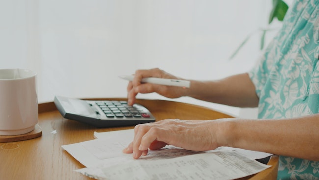 Hands of a person using a calculator and paying bills.