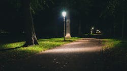 A streetlamp next to a path in a park A streetlamp next to a path in a park
